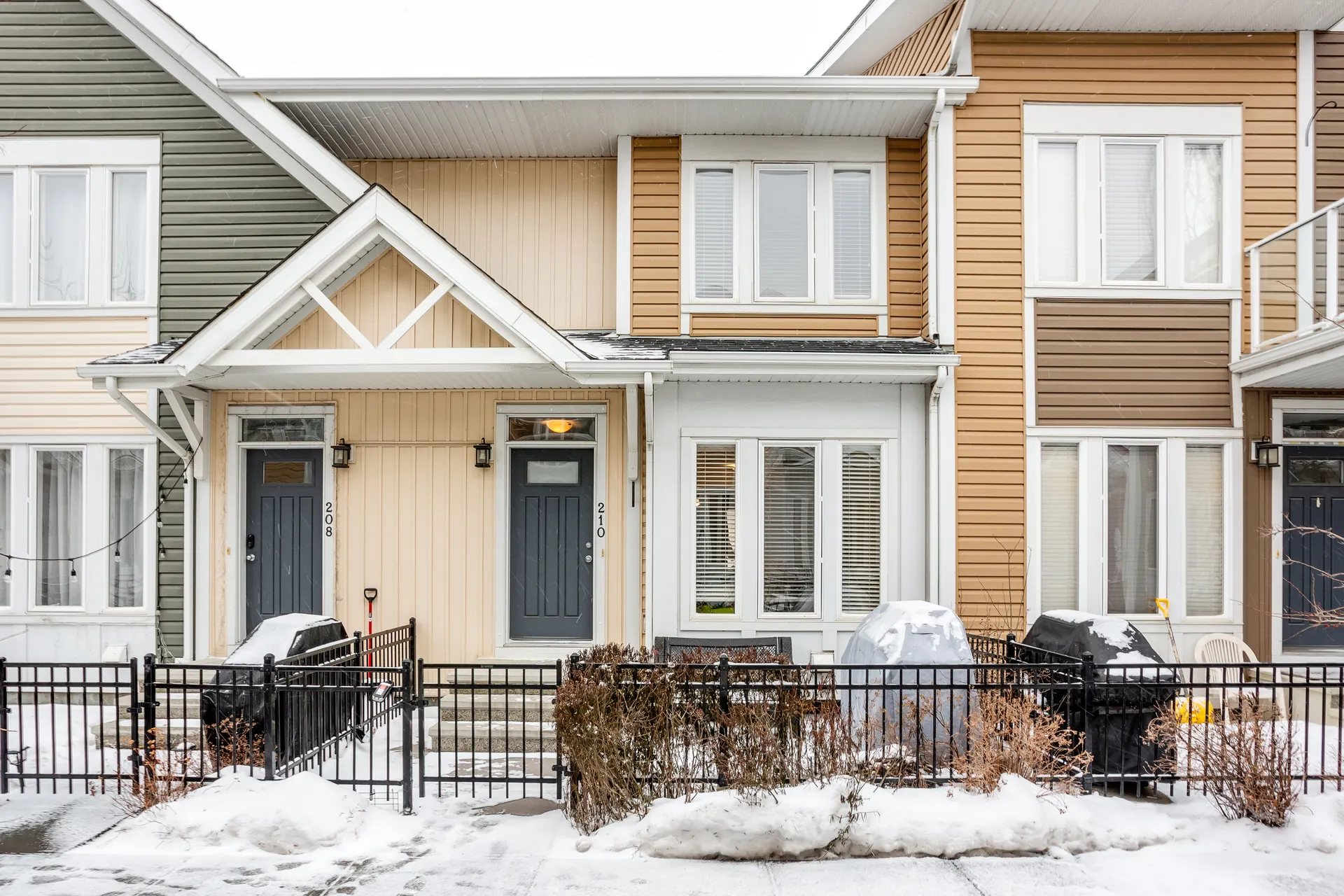 Two-storey townhomes with front fences on Auburn Bay Square SE in winter