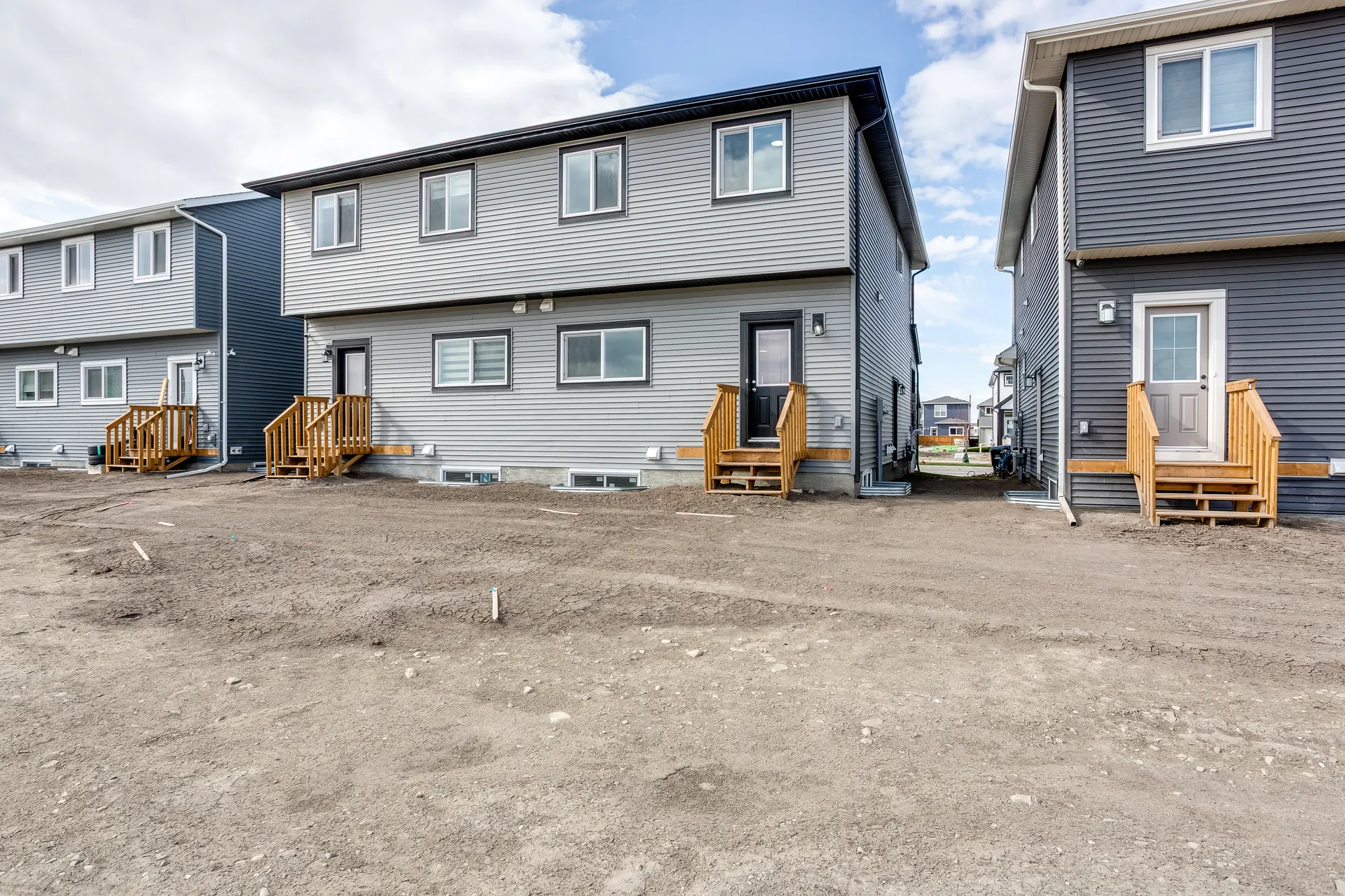 Rear of new homes with unfinished yards in Cobblestone Creek, Airdrie