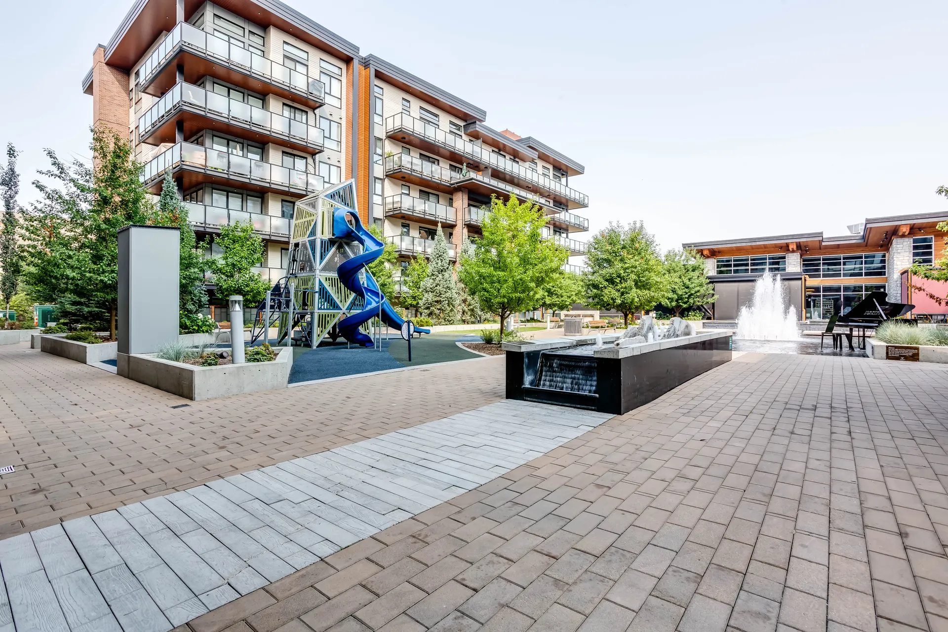 Paved courtyard with trees and apartment buildings in Mahogany, Calgary